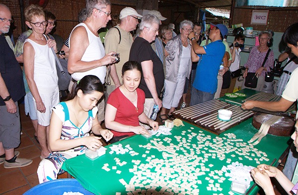 Một nhóm du khách nước ngoài tham quan lò làm kẹo dừa ở miền Tây